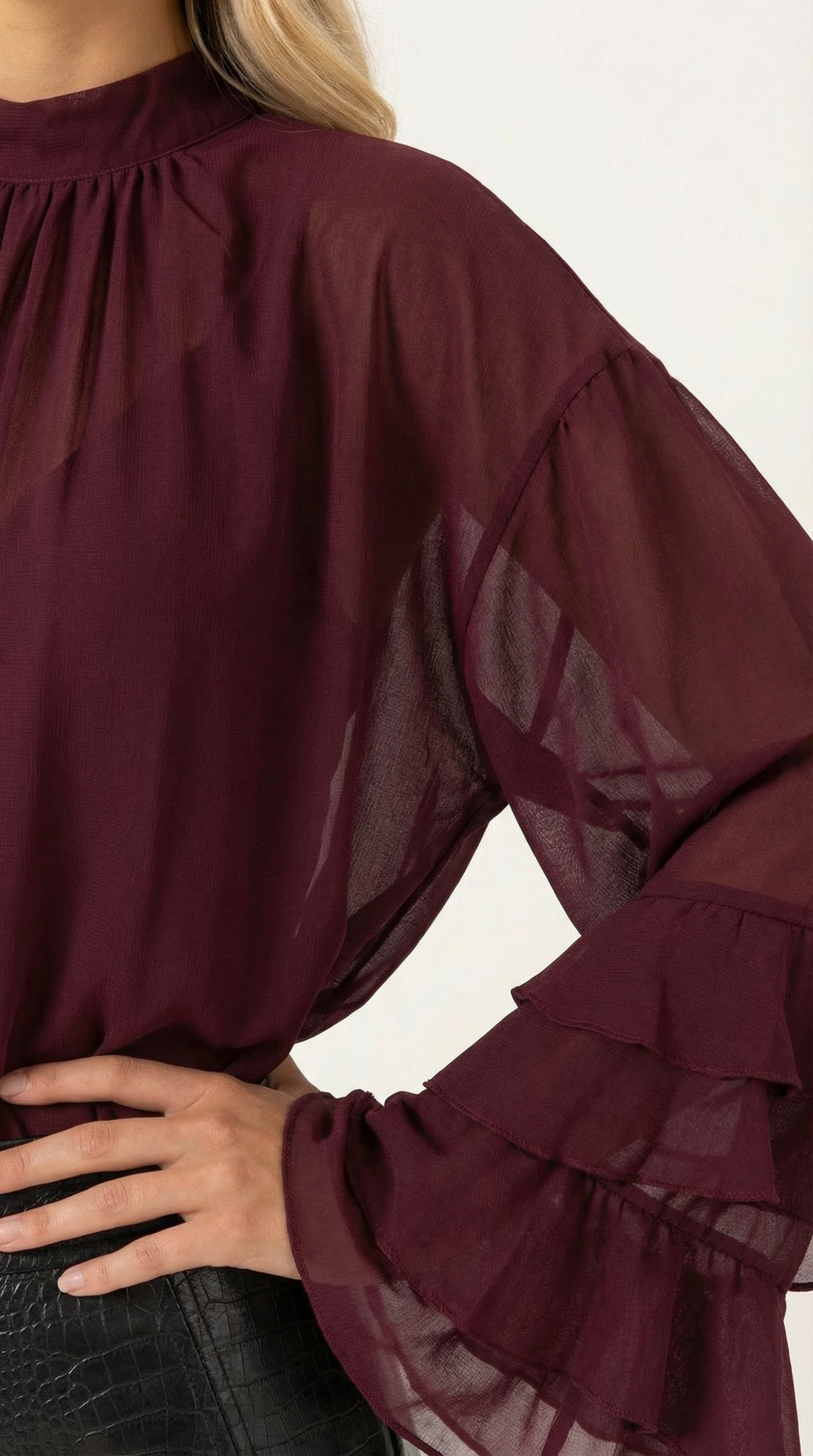 Burgundy sheer top close view: ruffled sleeve cuffs and high mock neck